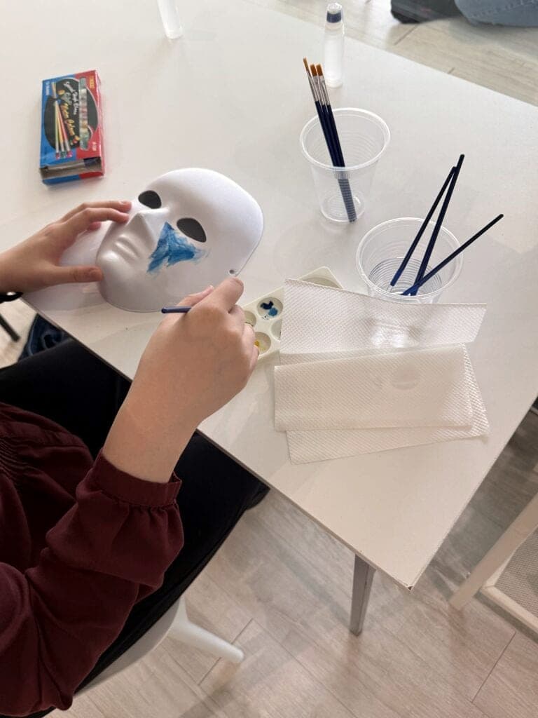 Hands painting a white mask at a Safe Space workshop